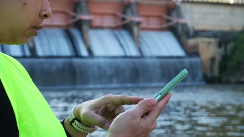 Environmental engineer uses a mobile phone to record water analysis data in dam. Stock Footage 229711919