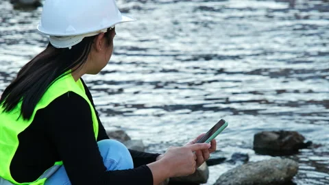 Environmental engineer uses a mobile phone to record water analysis data in dam. Stock Footage 229712426