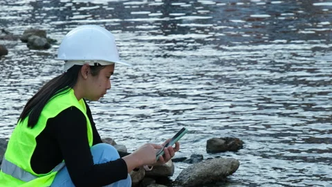 Environmental engineer uses a mobile phone to record water analysis data in dam. Stock Footage 229713978