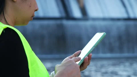Environmental engineer uses a mobile phone to record water analysis data in dam. Stock Footage 229713979