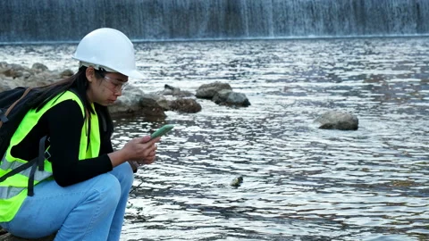 Environmental engineer uses a mobile phone to record data at a dam. 動画素材 229714606