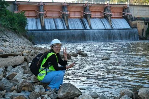 Environmental engineer uses a mobile phone to record water analysis data in dam. Foto stock