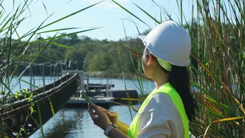 Environmental engineer working with mobile phone at reservoir Stock Footage 229708033
