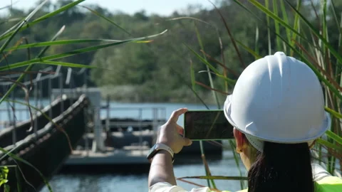 Environmental engineer working with mobile phone at reservoir Stock Footage 229708402