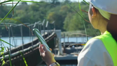 Environmental engineer working with mobile phone at reservoir Stock Footage 229708800