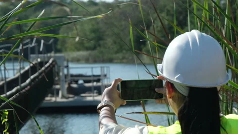 Environmental engineer working with mobile phone at reservoir Stock Footage 229708869