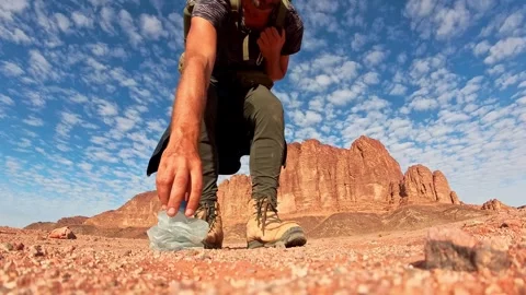 Environmental hiker picks up old plastic bottle waste in Wadi Rum desert, J.. Vídeos de archivo 330260189