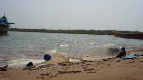 Environmental Pollution Concept Featuring Empty Plastic Trash on Sandy Beach Stock Photos