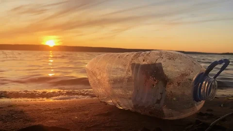 Environmental problem. Polluted beach. A bottle of plastic on the beach. Sunset Stock Footage 114712920