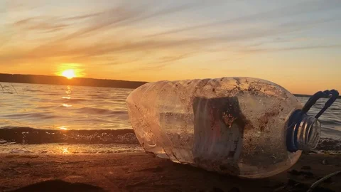Environmental problem. Polluted beach. A bottle of plastic on the beach. Sunset  Stock Footage 114713021