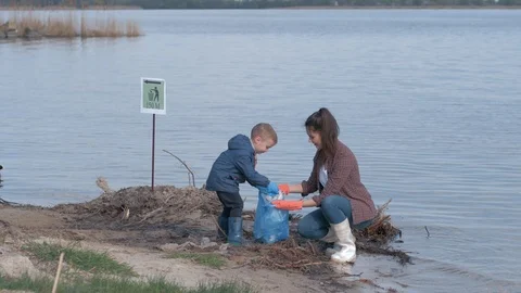 Environmental saving, kid boy helps mother volunteer activist clean up polluted Stock Footage 108169319