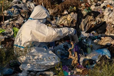 An environmental worker in protective gear is sorting through trash in a la.. Stock Photos