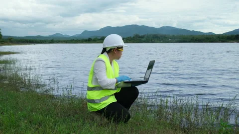 Environmentalist working on laptop to detect contaminant in natural water bodies Stock Footage 197451546