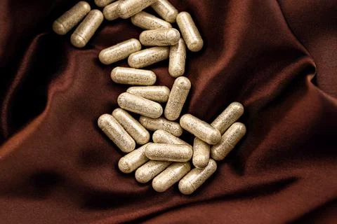 Enzymes capsules on silk background. mental wellbeing and personal health 库存照片