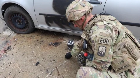 EOD soldier holding trigger wire of IED near vehicle during training Stock Footage 111947830