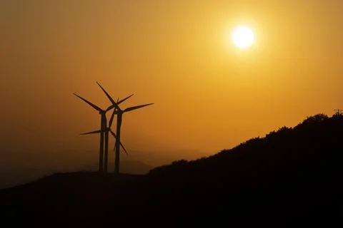 Eolic wind generators spinning in the mountains at sunset Stock Photos