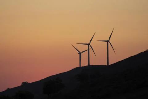 Eolic wind generators spinning in the mountains at sunset Stock Photos