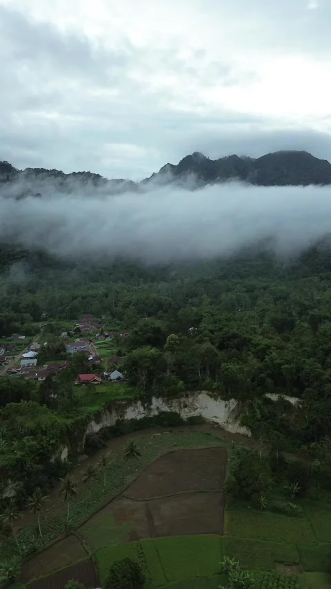 Ephemeral Mist Embracing Ancient Peaks Above a Serene Hamlet and Meandering.. Stock Footage 337279617