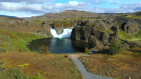 Epic aerial drone view flying over landscape of Hjalparfoss waterfall and lagoon Video stock 121250375