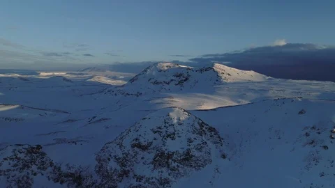 Epic aerial flying forward towards snow covered hills with partly cloudy sky. 库存影片 88296256