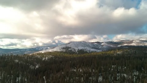 Epic aerial flying sideways over forest with snow and mountains in the distance. Video stock 148719451