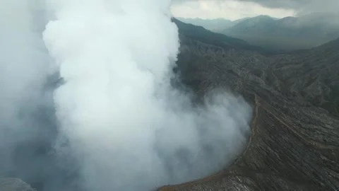 Epic aerial view of active volcano crater emitting thick white smoke into sky Stock Footage 295764010