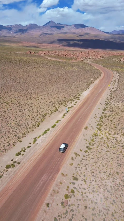 Epic aerial view of car driving on winding dirt road across vast desert plains 库存影片 340992372