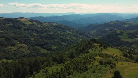 Epic aerial view flying forward over green hills revealing distant mountains Vídeos de archivo 342242271