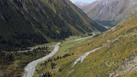 Epic aerial view of snow-capped Tian Shan peaks and winding river in valley 库存影片 334623779