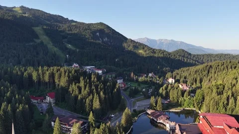 Epic aerial view of a tranquil mountain lake and resorts with peaks on horizon Stock Footage 344908664