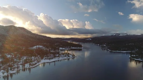 Epic backwards aerial shot over lake in winter, dazzling bright sun. Bass lake. Video stock 104234873