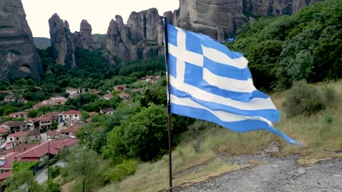 Epic Close Up of Torn Greek Flag Blowing in Wind. With Village and Mountain.. Stock Footage 334896608