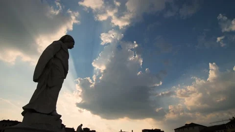 Epic clouds and sunset sky behind the silhouette of a religious stone statue. Stock Footage 157340189