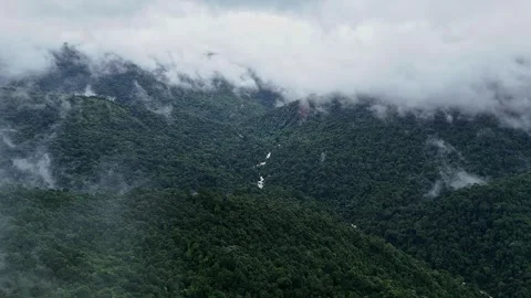 An epic drone view of a cascading waterfall lush mountains and forests topp.. Video stock 314207671
