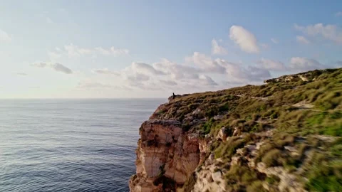 Epic fast flight past a tourist looking at sunset Dingli Cliffs on Malta 스톡 동영상 237458002