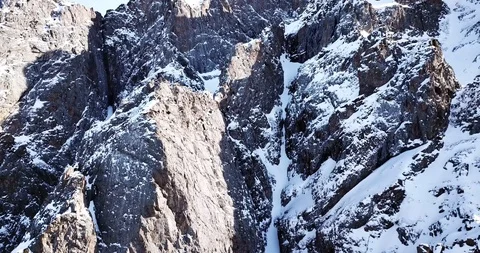 Epic fly on the drone rock covered with snow. Steep rocks among the snow. Stock Footage 100704718