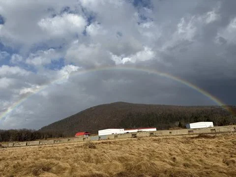 Epic Full Rainbow Arching Over Towering Mountain Range Stock Photos