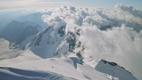 Epic magic clouds floats under snow summit, climbers ascend to mountain top Stock Footage 126363779