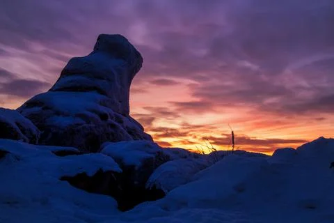 Epic red sunset over the rocks and stones of Ural mountains covered with snow Stock Photos