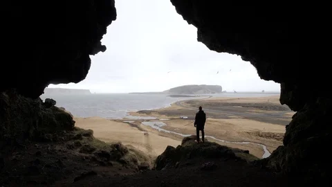 Epic shot of man watching landscape from a cave Stock Footage 107601228