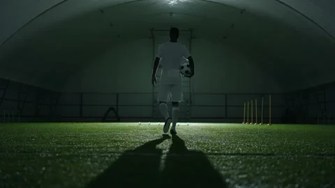 Epic slow motion shot with walking footballer with ball in indoor arena, rear Stock Footage 228958294