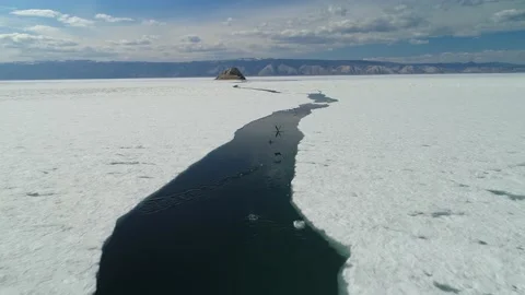 Epic spring icy Baikal crack flight cormorants birds fly over ice floes 4k Video stock 204121429