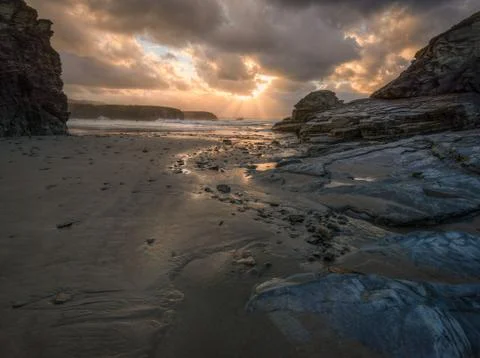 Epic sunset illuminates water paths left by the low tide in a beach Stock Photos