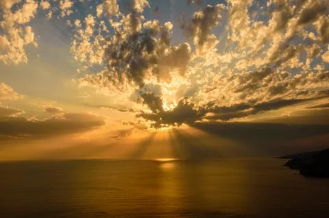 Epic sunset rays over sea and cloudy golden sky. Stock Photos