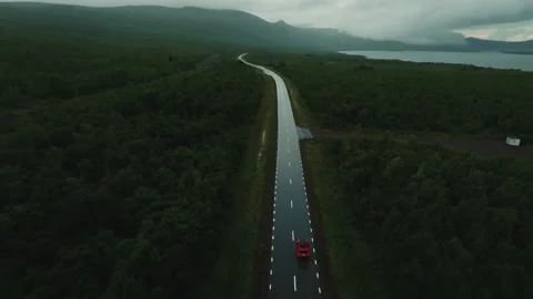 Epic top view of red SUV car driving alone on empty road amidst the beautiful Stock Footage 246416206