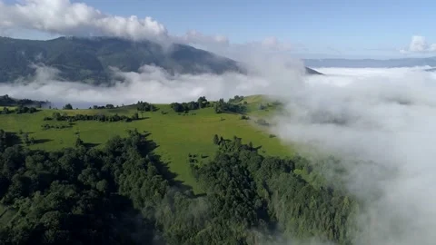 Epic view of mountains surrounded by clouds. Green grass and forests cover the 스톡 동영상 136086042