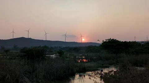 An epic view of a summer sunset over mountains with wind turbines slowly ro.. Stock Footage 313381919