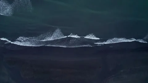 Epic Wide Black Sand Beach At Dusk. Girl In Orange Jacket Walks on Shore Stock Footage 258508674