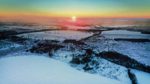 Epic winter sunset, icy landscape with veins of power, distant industry. Aerial Stock Footage 257784374