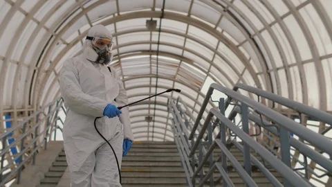 Epidemiologist in protective uniform disinfects surface in public place Video stock 127152741